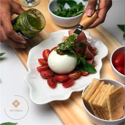 Burrata: Burrata de búfala, presunto parma, molho pesto, baguete, torrada, tomatinhos e folhas